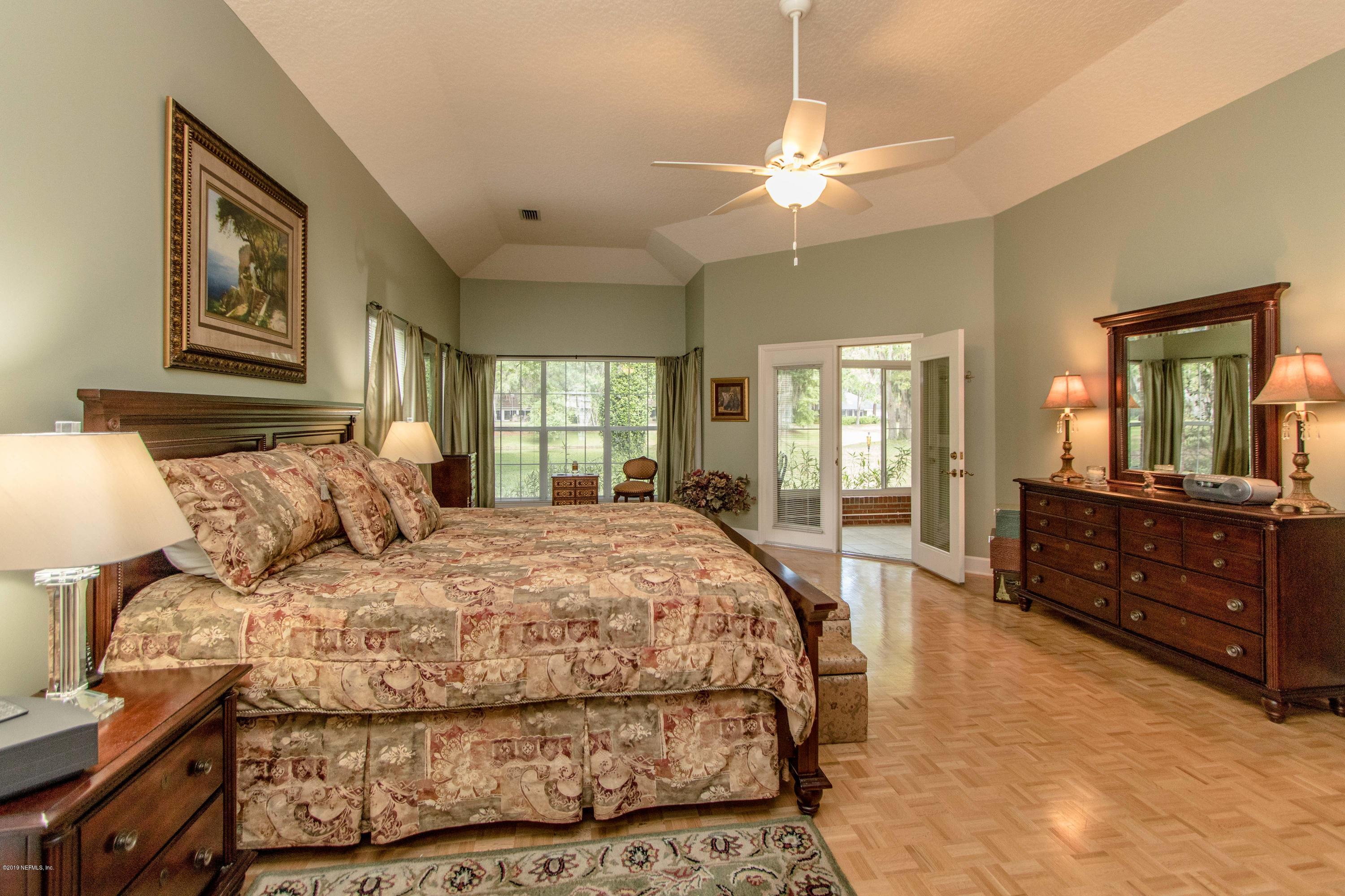 1944 Salt Myrtle Lane Fleming Island, FL 32003 - Photo 23 of 76 a bedroom with a large bed and a chandelier