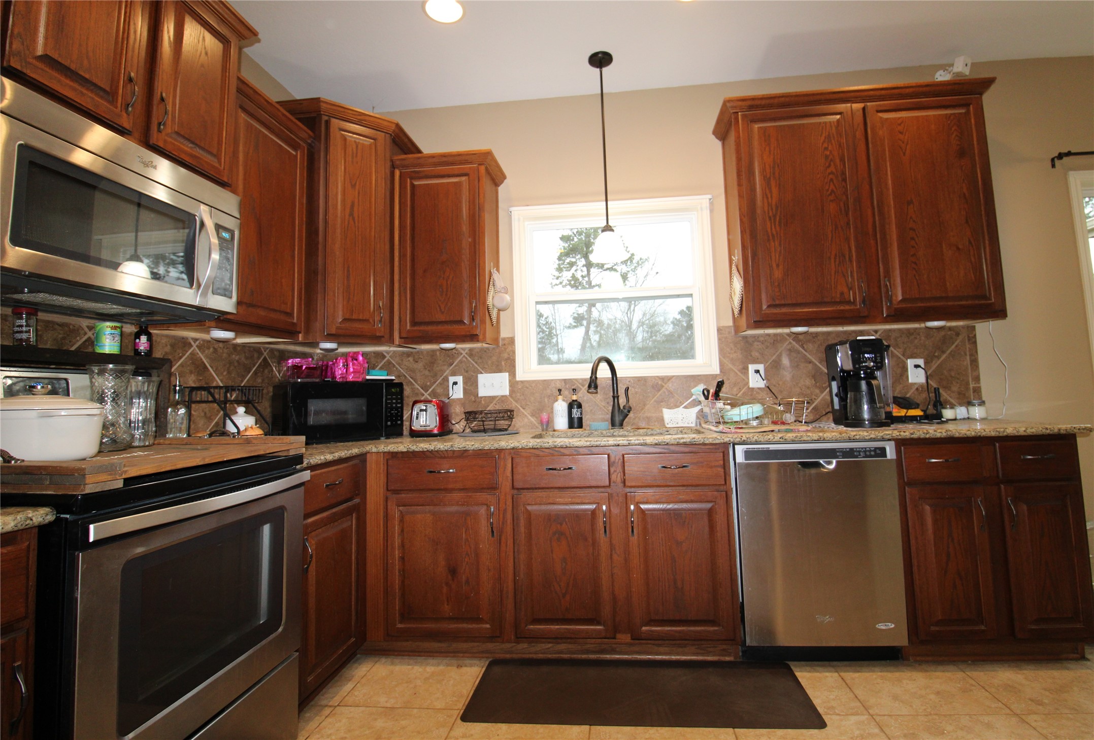 14620 Lyric Road Conroe, TX 77302 - Photo 13 of 43 a kitchen with stainless steel appliances a sink a stove a microwave cabinets and a counter top space