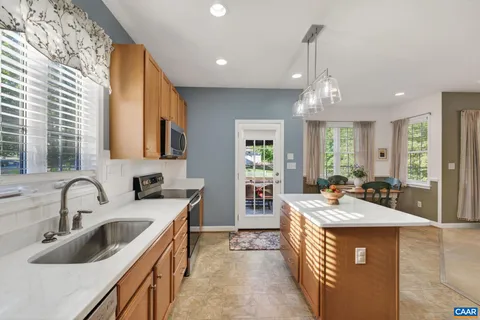 a kitchen with stainless steel appliances kitchen island granite countertop a refrigerator a stove top oven a sink dishwasher and couches with wooden floor
