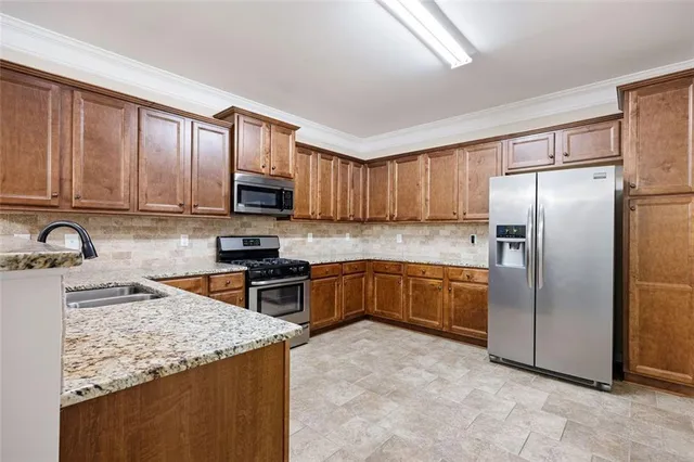 a kitchen with granite countertop a refrigerator stove top oven a sink and dishwasher