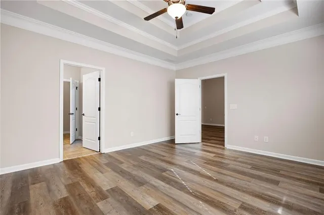 wooden floor in an empty room with a chandelier fan