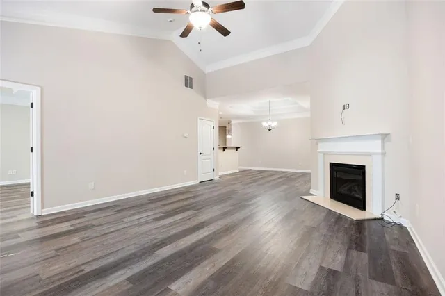 an empty room with wooden floor fireplace and windows