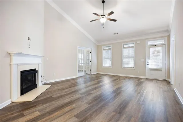 a view of an empty room with wooden floor fireplace and a window