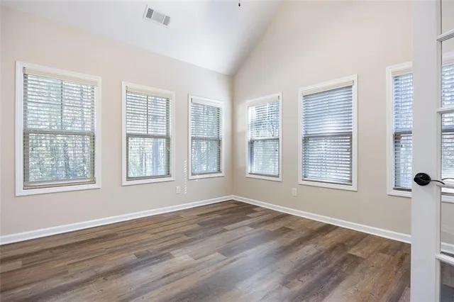 a view of an empty room with wooden floor and a window