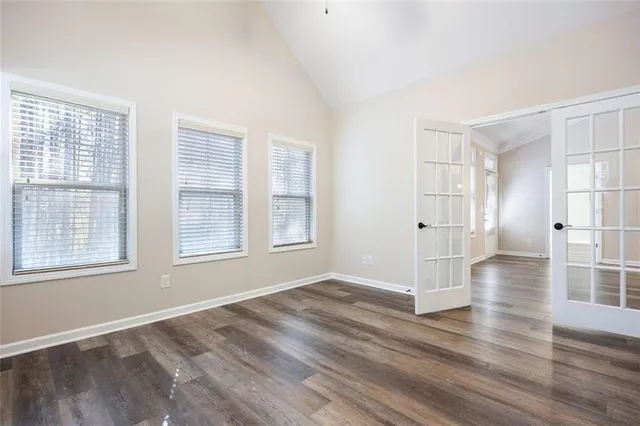 an empty room with wooden floor and windows