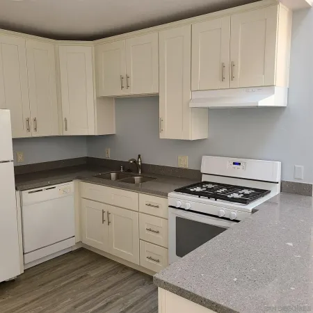 a kitchen with granite countertop white cabinets and stainless steel appliances