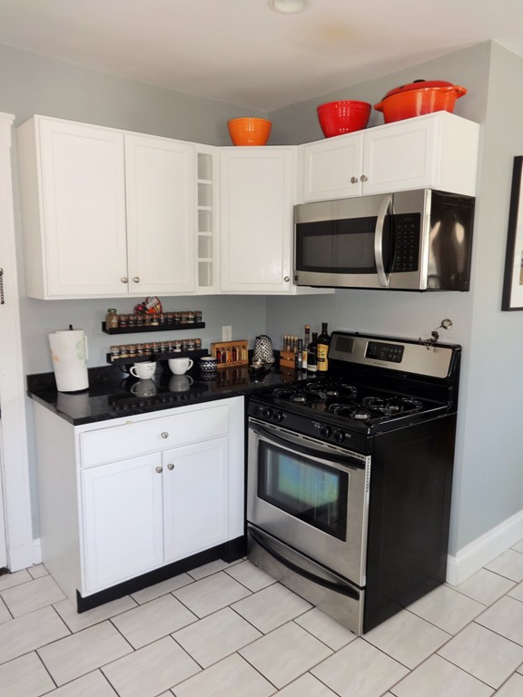 37 Everett Street, Unit 3 Waltham, MA 02453 - Photo 11 of 16 a kitchen with stainless steel appliances granite countertop a stove and a microwave