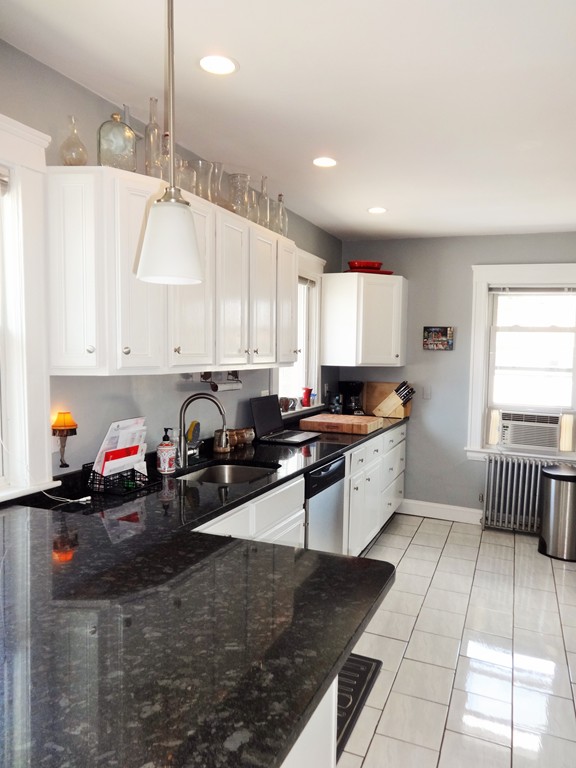37 Everett Street, Unit 3 Waltham, MA 02453 - Photo 9 of 16 a white kitchen with granite countertop a stove a sink a window and white cabinets