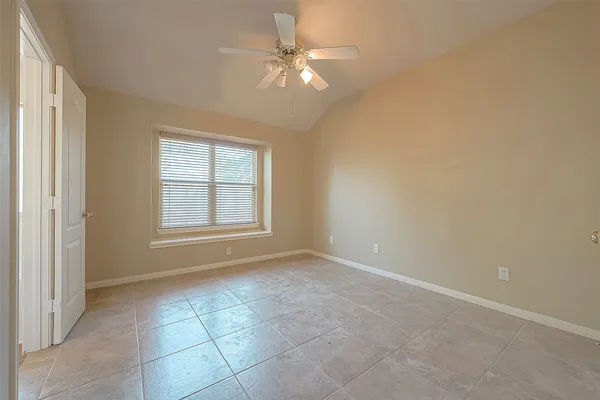 an empty room with chandelier fan and windows