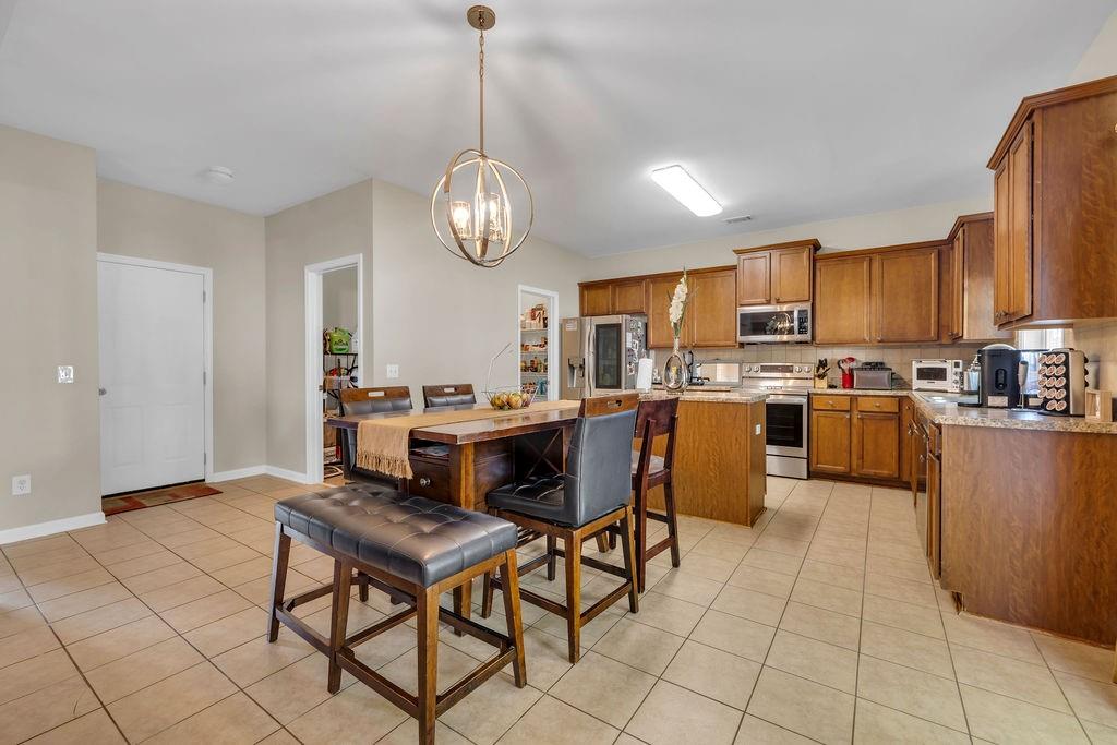 126 Meadow's Walk Drive Byron, GA 31008 - Photo 17 of 37 a open kitchen with stainless steel appliances kitchen island granite countertop a refrigerator a stove a sink dishwasher and a dining table with wooden floor