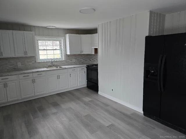 a kitchen with granite countertop white cabinets and refrigerator