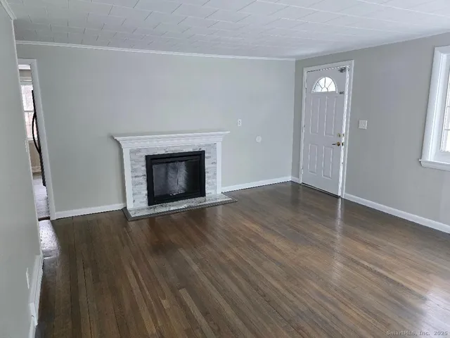 an empty room with wooden floor fireplace and windows