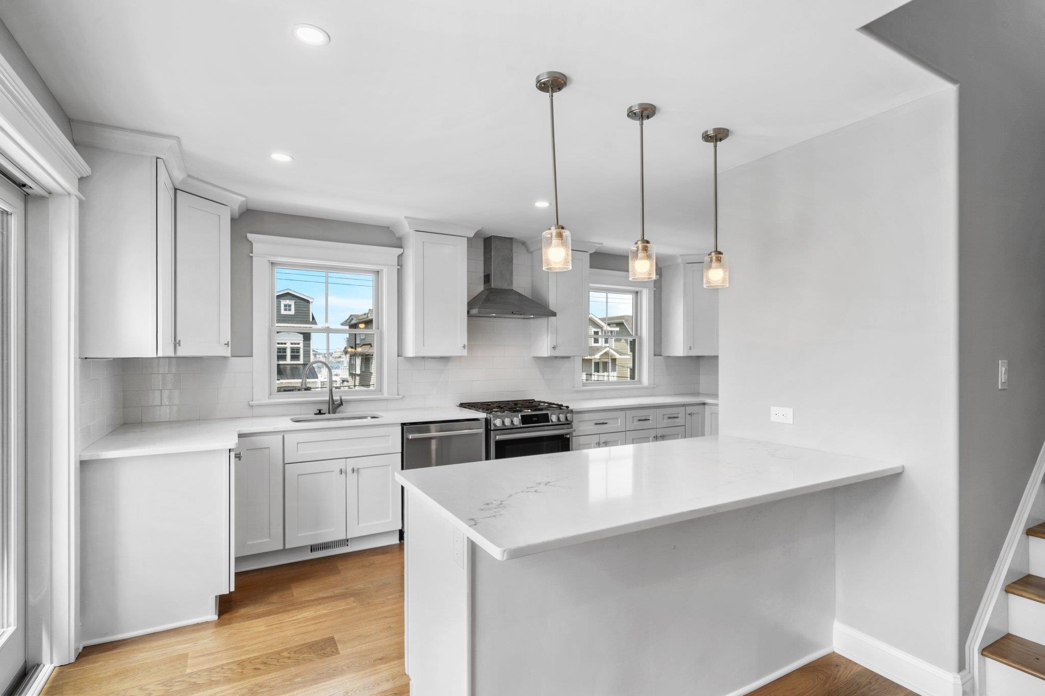 297 24th, Unit 297 Avalon, NJ 08202 - Photo 32 of 49 a kitchen with stainless steel appliances kitchen island granite countertop a sink a stove and white cabinets