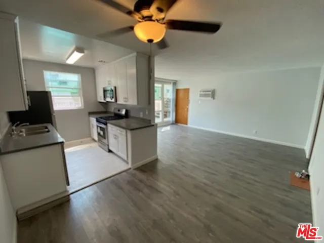 a kitchen with stainless steel appliances granite countertop a sink cabinets and wooden floor