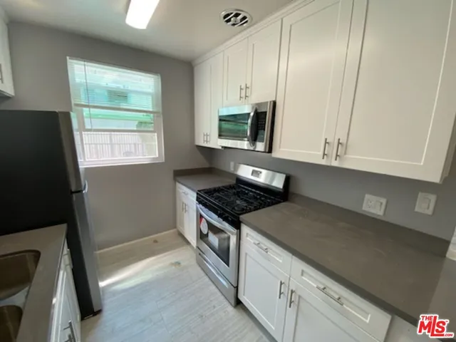 a kitchen with stainless steel appliances granite countertop a stove a sink and a microwave