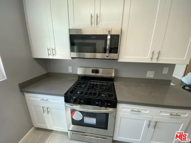 a kitchen with white cabinets and stainless steel appliances