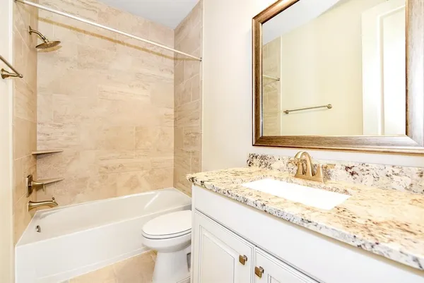 a bathroom with a granite countertop sink a toilet and shower