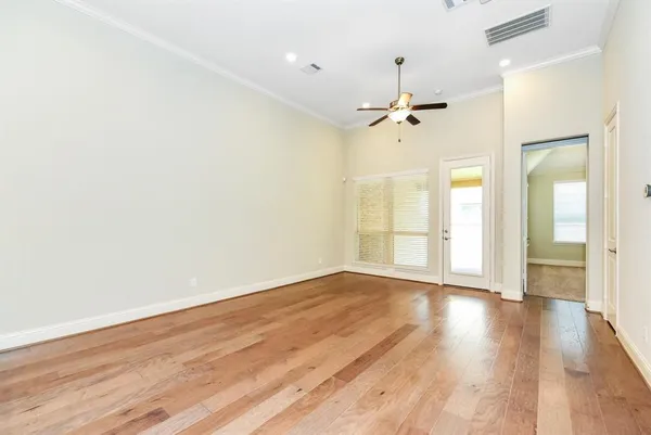 an empty room with wooden floor ceiling fan and windows