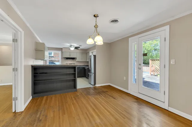 a view of an empty room with window and wooden floor
