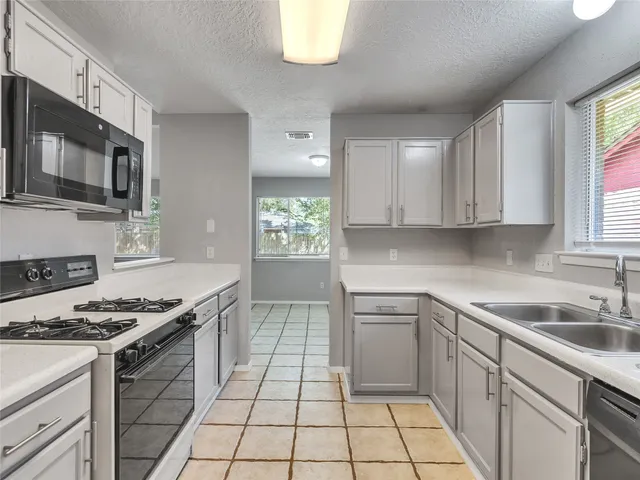 a kitchen with stainless steel appliances granite countertop a sink a stove a microwave and cabinets