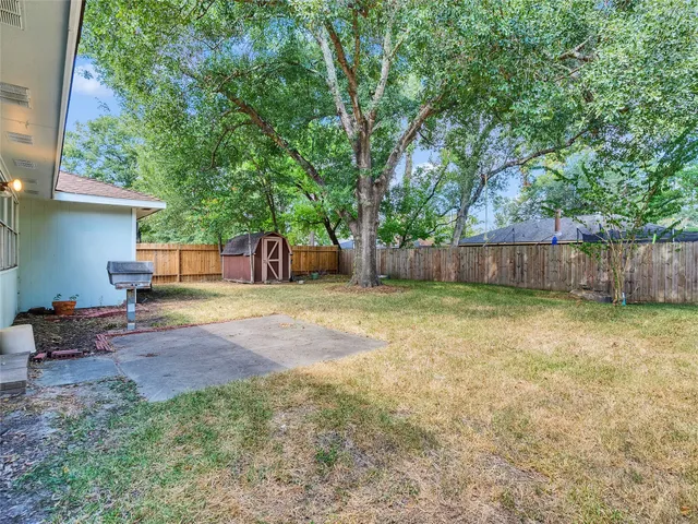 a view of a backyard with large trees and wooden fence
