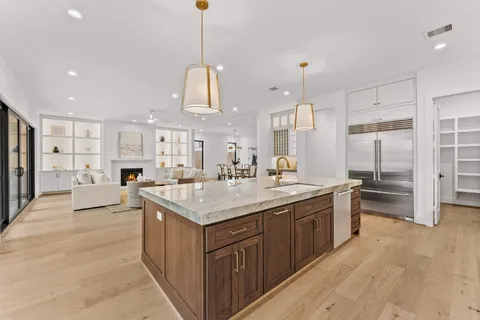 a kitchen with stainless steel appliances granite countertop a sink a stove a refrigerator and island with wooden floor