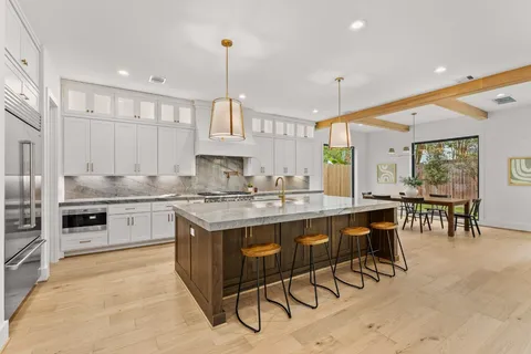 a kitchen with stainless steel appliances granite countertop a stove top oven a sink dishwasher a dining table and chairs with wooden floor