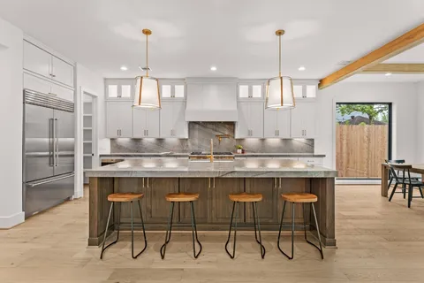 a kitchen with kitchen island granite countertop a table chairs sink and cabinets