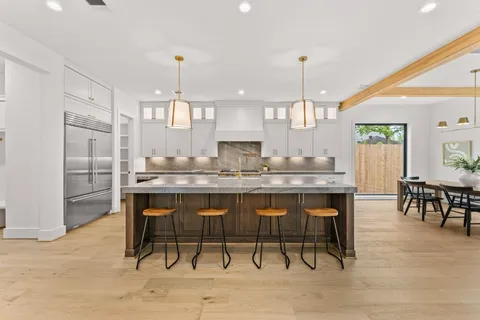 a kitchen with kitchen island granite countertop a table chairs sink and cabinets