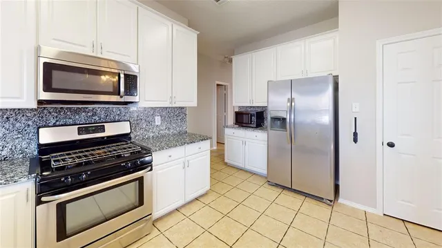 a kitchen with stainless steel appliances granite countertop a stove a microwave and a refrigerator