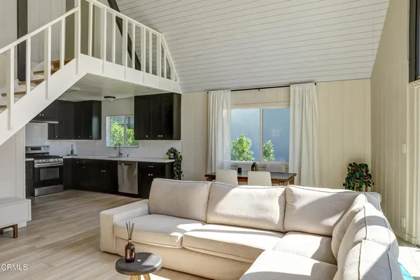 a living room with furniture kitchen view and a large window