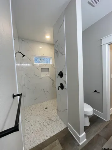 a bathroom with a granite countertop sink a toilet and shower