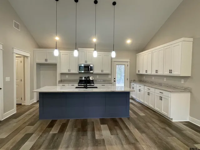 a large kitchen with kitchen island a sink stainless steel appliances and cabinets