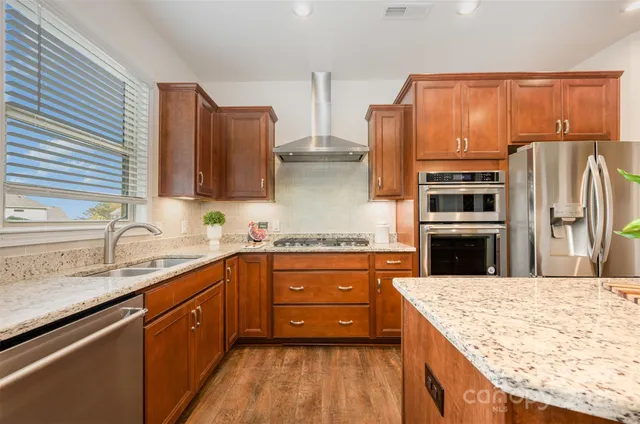 a kitchen with stainless steel appliances granite countertop wooden cabinets a stove and sink