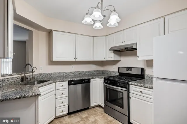 a kitchen with granite countertop stainless steel appliances a stove sink and cabinets