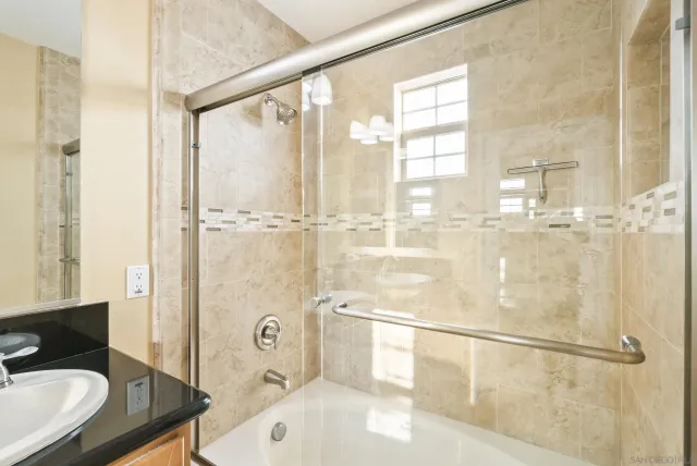 a bathroom with a granite countertop sink mirror and a bathtub