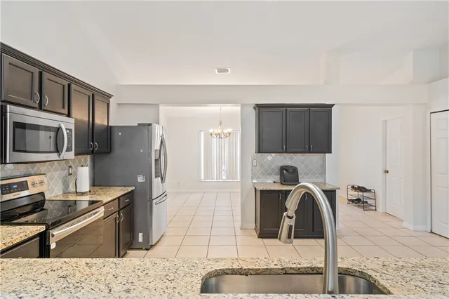 a kitchen with stainless steel appliances kitchen island granite countertop a refrigerator and a stove top oven