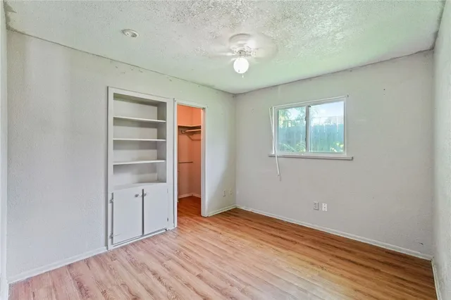 an empty room with wooden floor closet and windows
