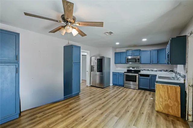 a kitchen with stainless steel appliances granite countertop a refrigerator a stove top oven a sink and dishwasher with wooden floor