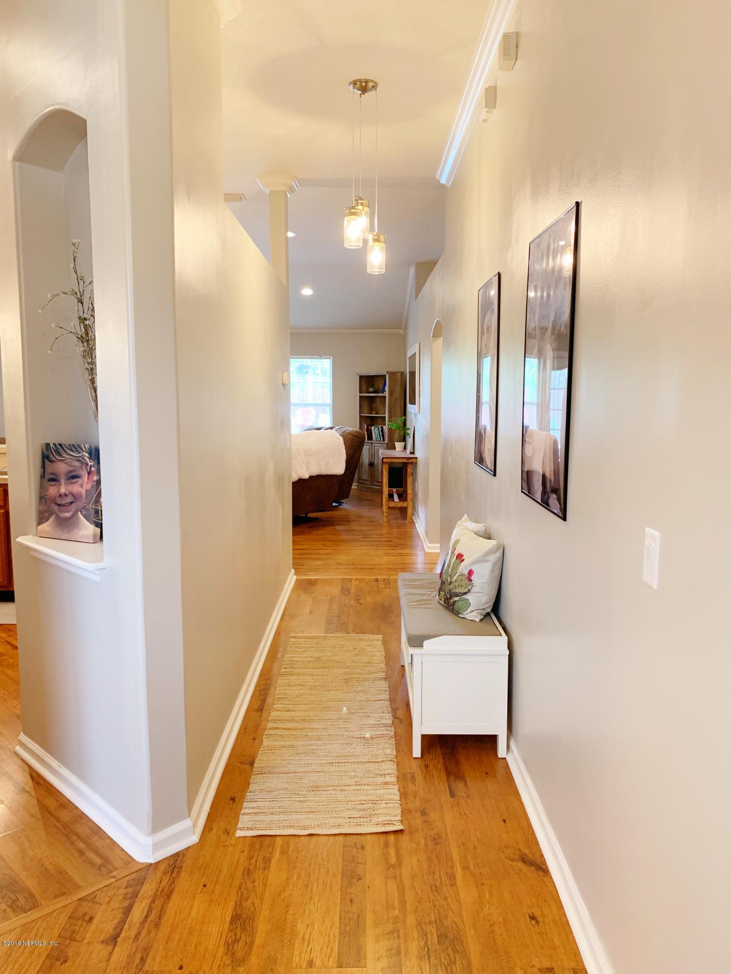 10345 Sugar Grove Road Jacksonville, FL 32221 - Photo 12 of 36 a hallway with a couch and dresser with wooden floor