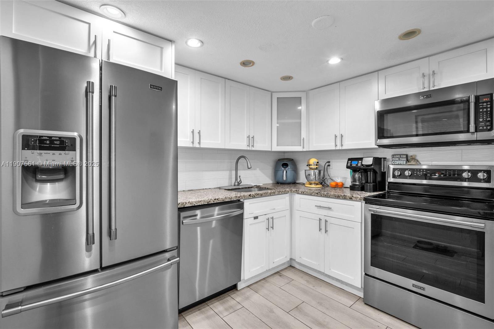a kitchen with stainless steel appliances granite countertop a refrigerator stove and sink
