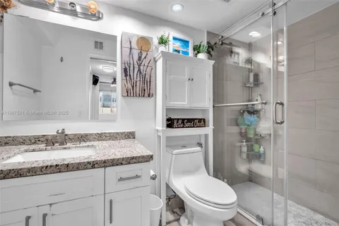 a bathroom with a granite countertop sink toilet and shower