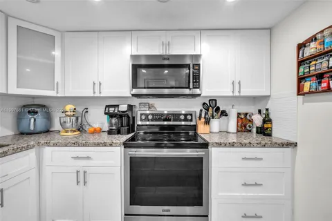 a kitchen with granite countertop white cabinets and appliances