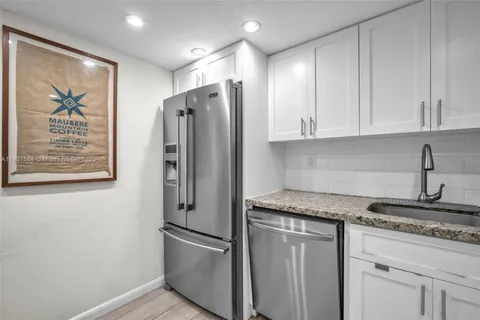 a kitchen with stainless steel appliances granite countertop a refrigerator and white cabinets