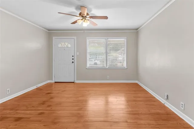 a view of an empty room with a window and wooden floor