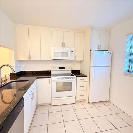 a kitchen with granite countertop white cabinets and white appliances
