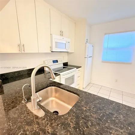 a kitchen with a sink a stove and white cabinets