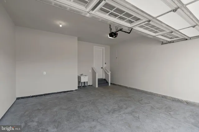 an empty room with wooden floor staircase and windows