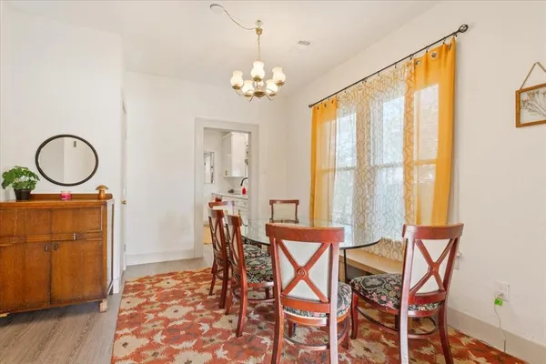 a dining room with chandelier and wooden floor