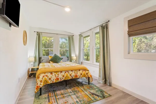 a bedroom with a bed a flat screen tv and next to a window